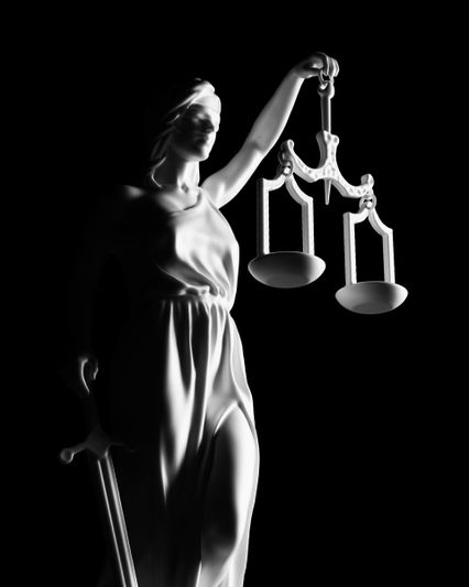 Statue de la Justice en noir et blanc, tenant une balance dans une main, une épée dans l'autre, symbolisant l'équité et la justice.