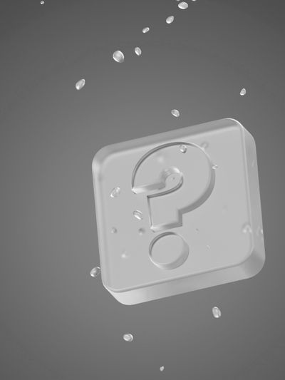 Un symbole de point d'interrogation en 3D enfermé dans du verre, entouré de gouttelettes d'eau flottantes sur un fond gris.