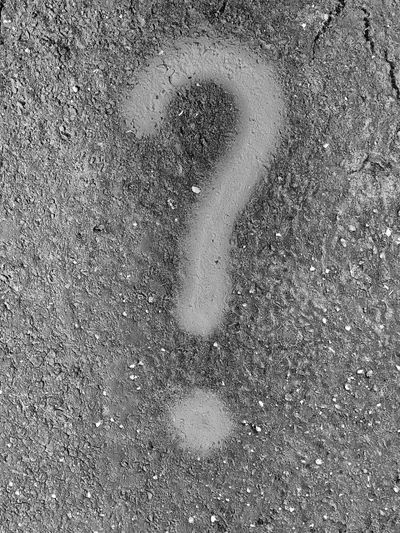 Un signo de interrogación blanco pintado con spray en una carretera asfaltada