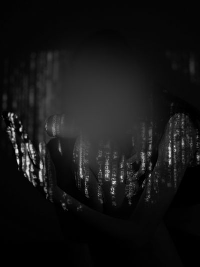 Silhouetted person with digital code projected on them, creating a mysterious and abstract effect in a dark setting.