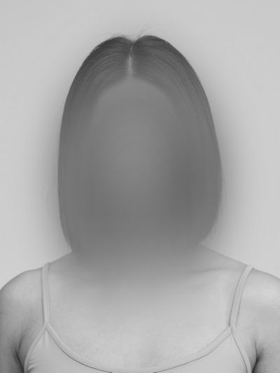 Fotografía en blanco y negro de una mujer con el pelo medio largo y un top de tirantes, cuyo rostro aparece desenfocado.