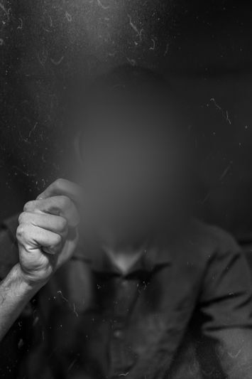 Personne au visage flou tenant un petit objet dans un environnement faiblement éclairé, créant une atmosphère mystérieuse et floue.