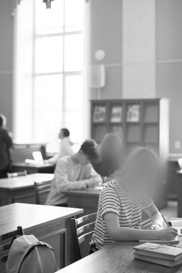 Un maestro se sienta en el suelo leyendo a cuatro niños pequeños en un aula luminosa. Los niños están reunidos alrededor, escuchando atentamente.