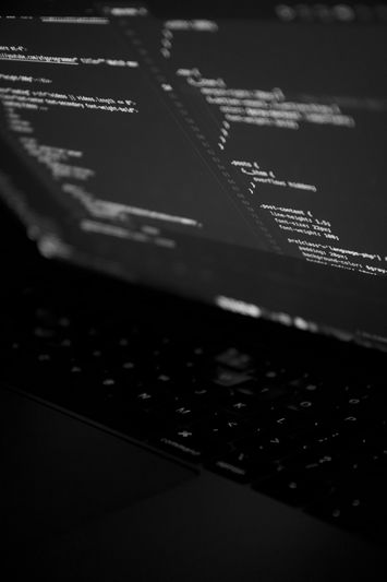 Close-up of a laptop screen displaying lines of code in a dark environment, highlighting programming text and syntax.