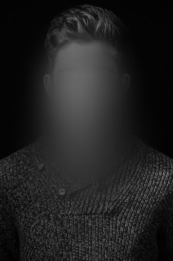 Monochromatyczny portret osoby z krótkimi włosami i widocznymi uszami; twarz zamazana gładkim rozmyciem; ubrana w sweter z fakturą dzianiny.