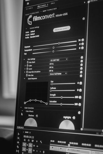 Gros plan d'un écran d'ordinateur affichant un logiciel de montage de film avec divers curseurs de réglage et paramètres en noir et blanc.