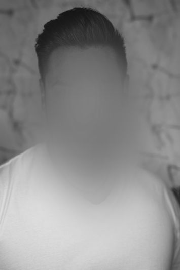 Fotografía en blanco y negro de un hombre con camiseta blanca y pelo corto, con el rostro difuminado.