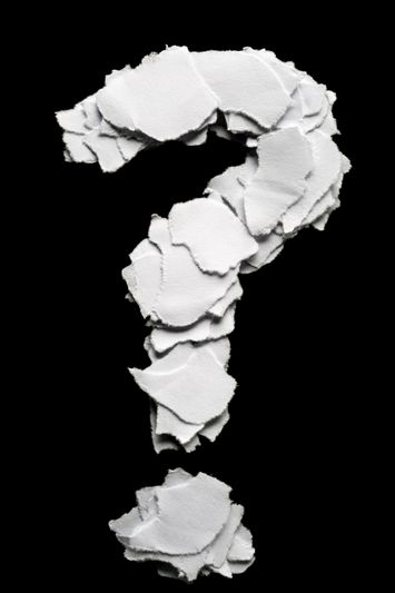 A question mark made of torn white paper pieces arranged on a black background.