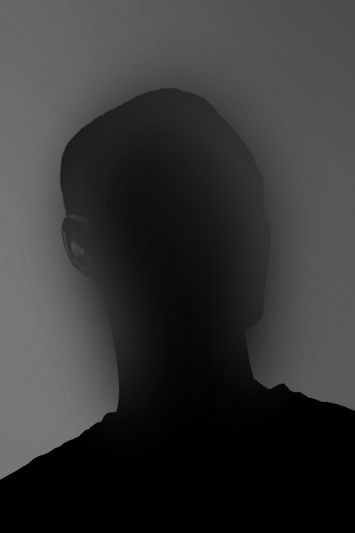 Hombre de piel negra con un suéter negro, posando para una foto de perfil derecho con el rostro desenfocado