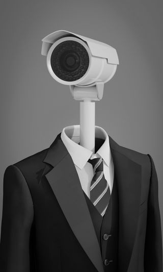 Une figure humanoïde en costume avec une caméra de surveillance en guise de tête, sur fond gris.