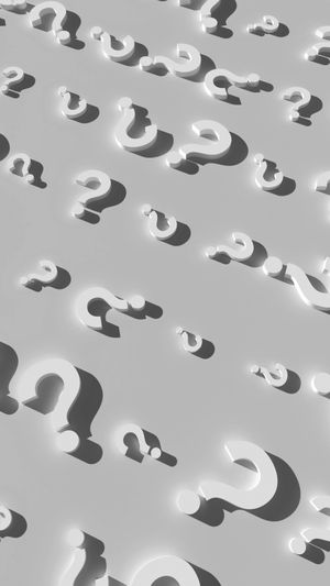 Un patrón de signos de interrogación 3D blancos proyectando sombras sobre un fondo gris claro, dispuestos en diagonal a lo largo de la imagen.