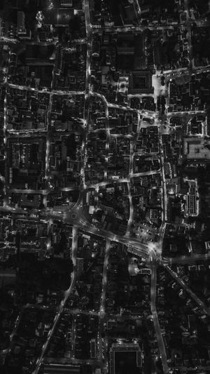Vue aérienne d'une ville la nuit, présentant des rues et des bâtiments illuminés dans un motif de grille complexe.