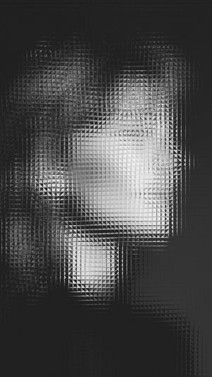 Image abstraite en noir et blanc avec un motif texturé en forme de grille masquant un visage humain en arrière-plan.