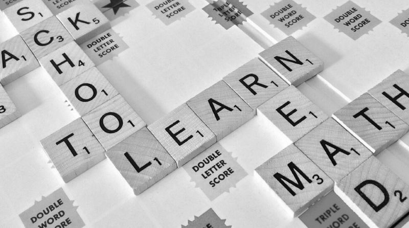 Scrabble tiles spell "BACK TO SCHOOL" and "LEARN MATH" on a game board, with score labels visible.