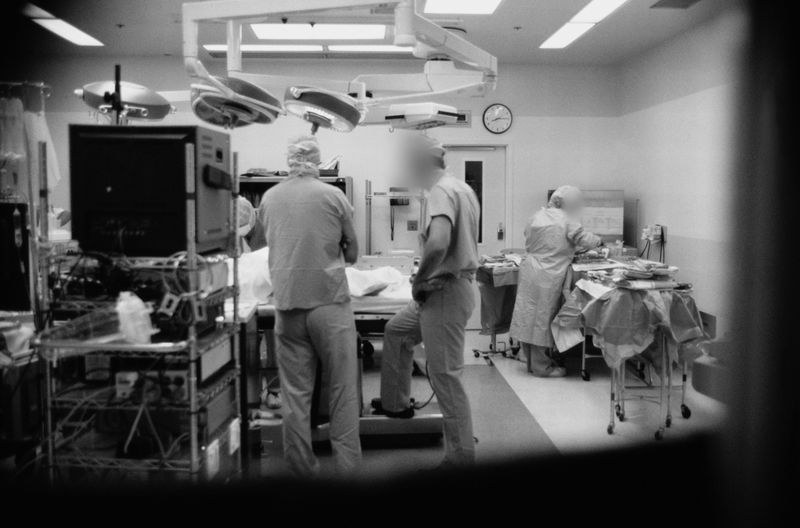 Medical team in an operating room, with surgical equipment and monitors, preparing for a procedure under bright overhead lights.