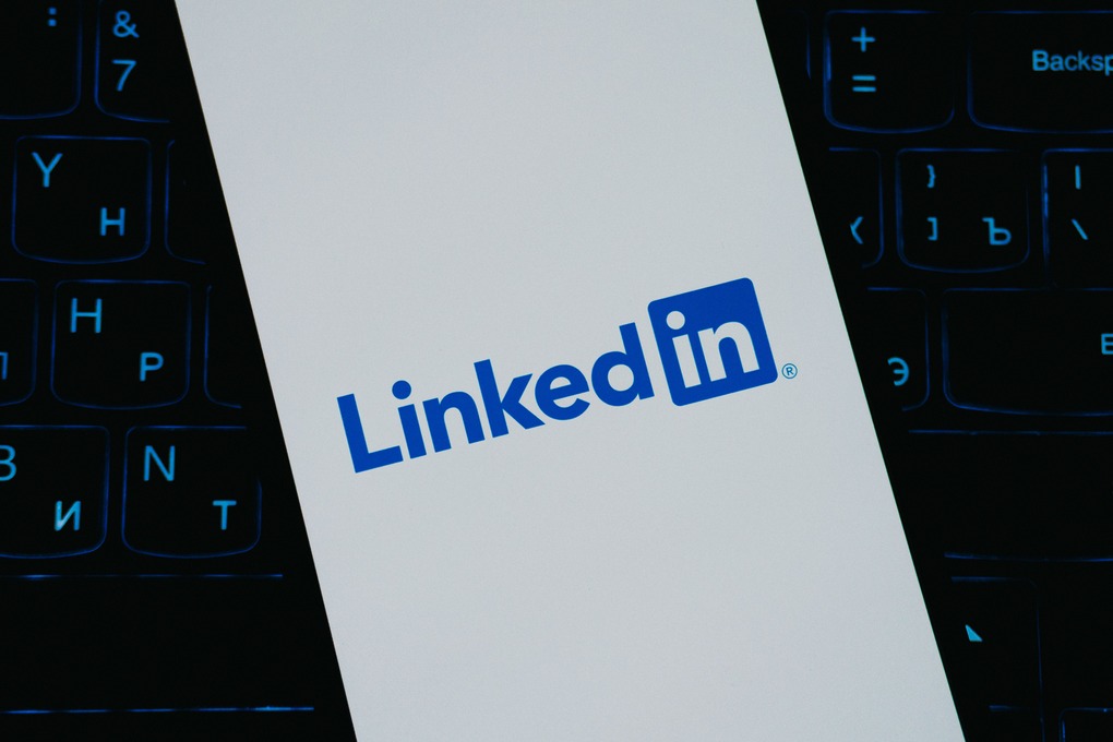 LinkedIn logo displayed on a smartphone screen with a blurred keyboard background.