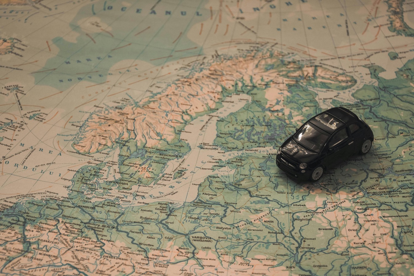 Small black toy car sitting on a vintage map of Scandinavia and northern Europe.