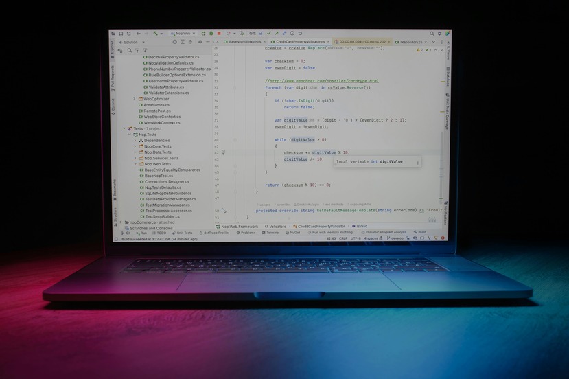 Laptop displaying code on a dark background with pink and blue lighting highlighting the keyboard.