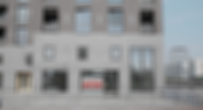 Ein großes, leerstehendes Bürogebäude an einem Kanal in der Stadt. Ein Schild von Engel & Völkers Commercial in der Mitte verrät, dass es sich um eine exklusive Gewerbefläche handelt, die zu vermieten ist. Eine große, knallige Überschrift sagt „Frage, Frage, Frage!“.
