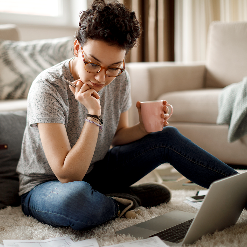 Frau mit Kaffee in der Hand am Laptop