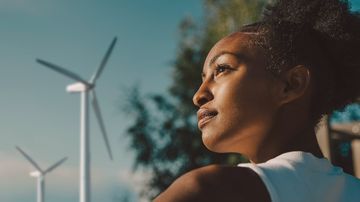 lächelnde Frau mit Windrädern im Hintergrund