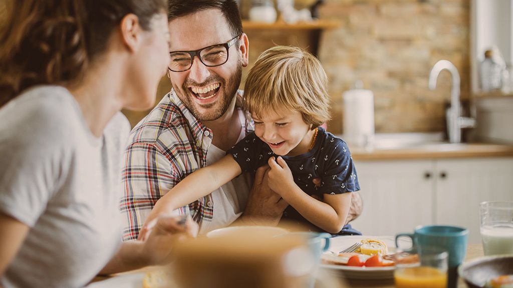 Familie sitzt lachend am Esstisch