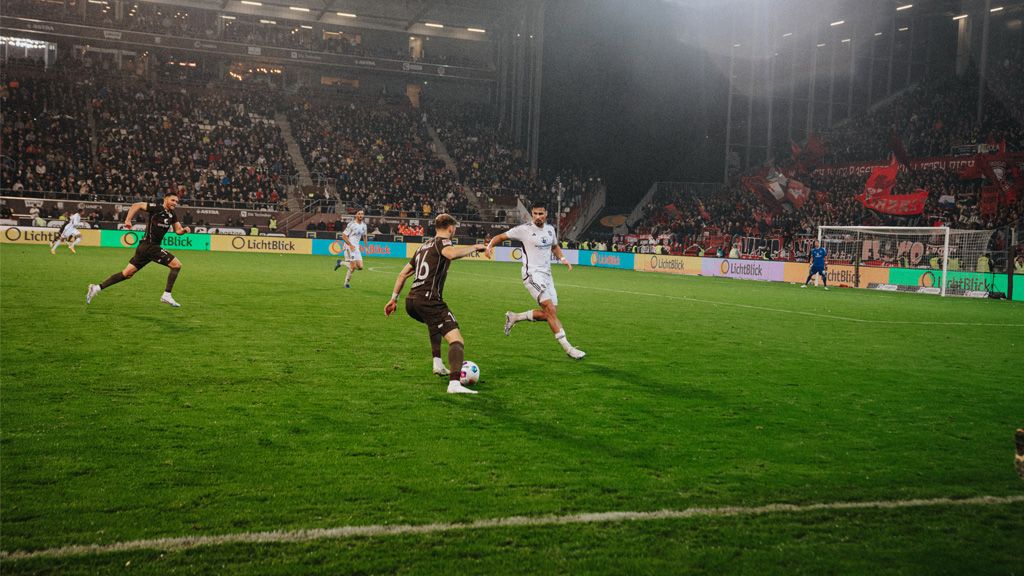 Fußballspieler des FC St. Pauli spielen im Stadion vor LichtBlick Bannerwerbung