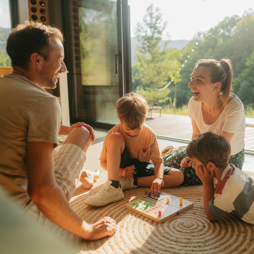 Familie spielt auf dem Fussboden ein Brettspiel