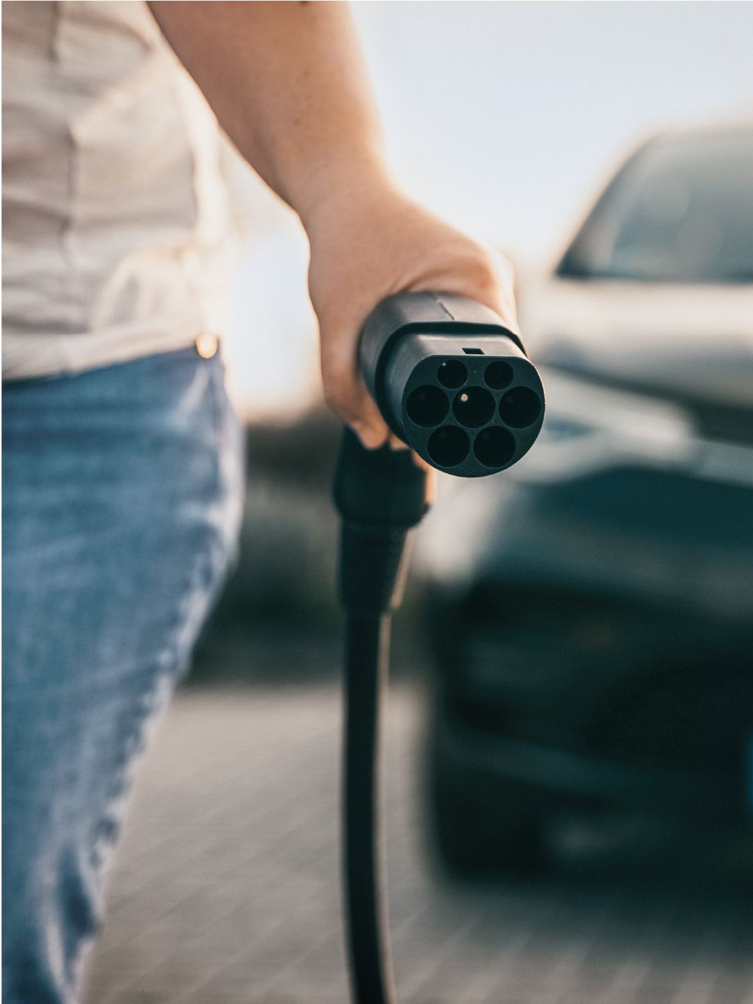 Mann hält Ladekabel zum Laden von E-Auto in der Hand