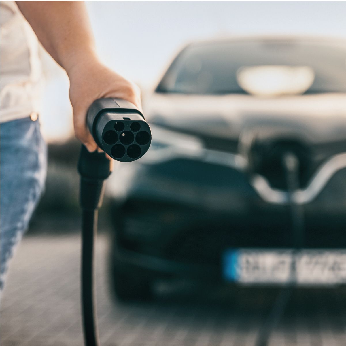 Mann hält Ladekabel zum Laden von E-Auto in der Hand