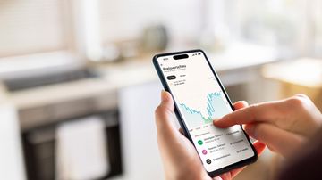 Frau hält Handy in der Hand und sieht negative Strompreise