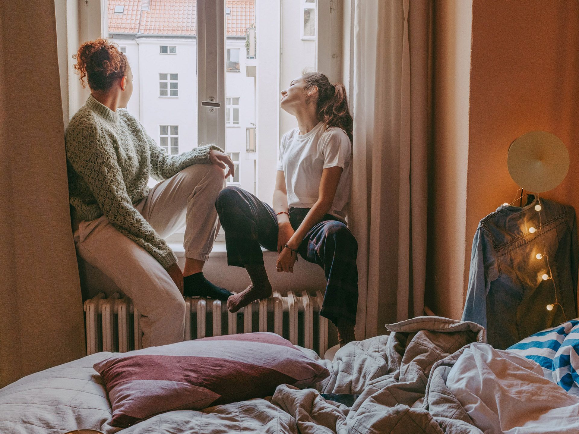 Zwei Frauen sitzen am Fenster über der Heizung