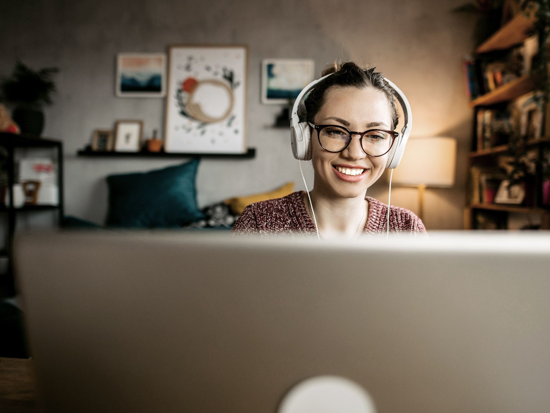 Frau mit Kopfhörern vor dem Laptop