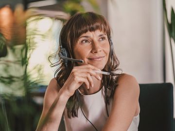 Frau mit Headset am Schreibtisch