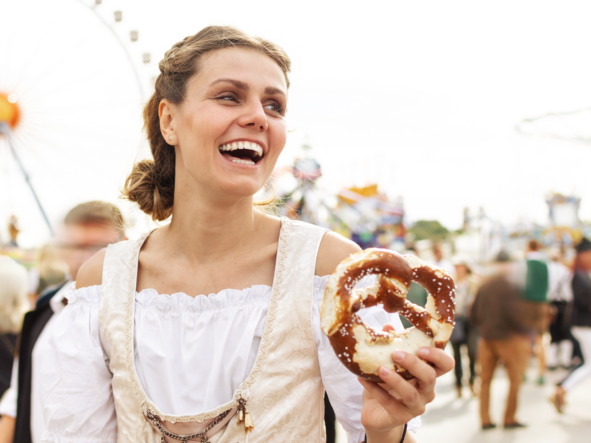 Frau im Dirndl mit Brezel in der Hand