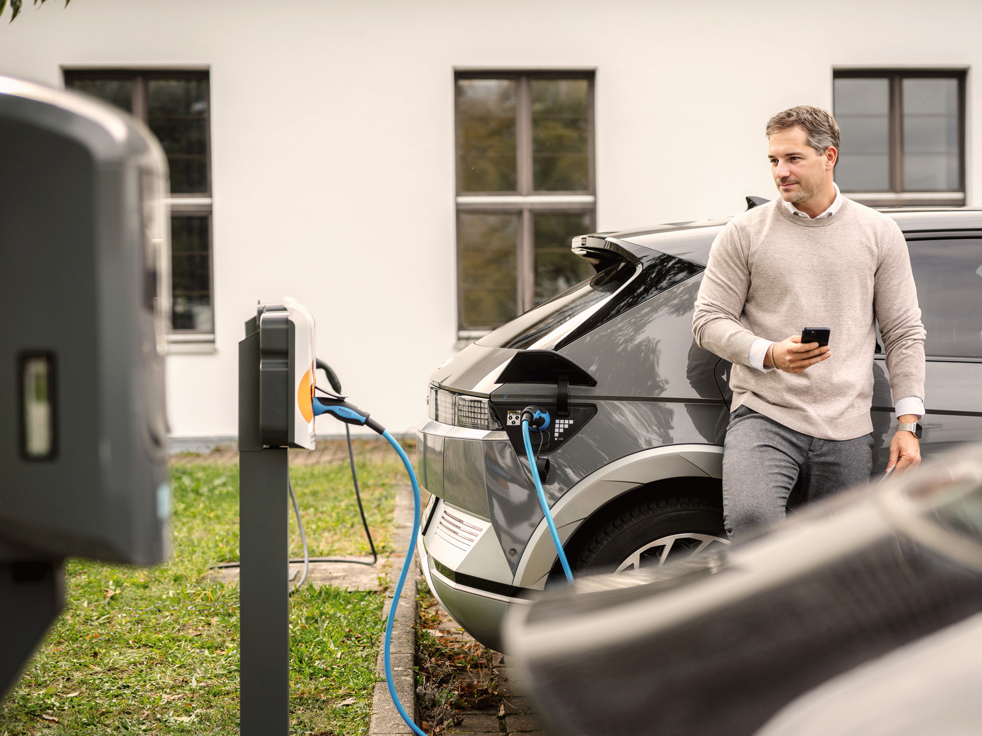 Mann laedt E-Auto an Ladestation