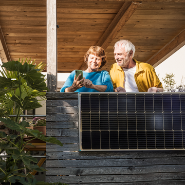Altes Ehepaar steht auf dem Balkon mit Balkonkraftwerk