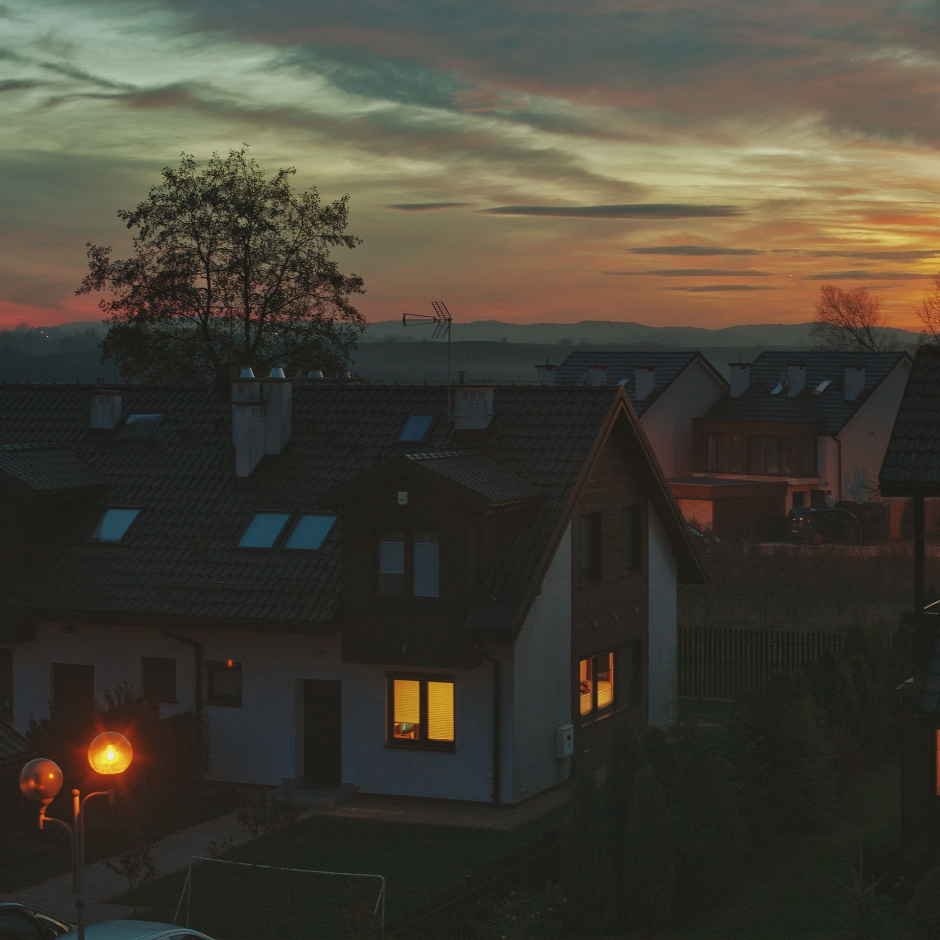 beleuchtete Haeuser mit Sonnenuntergang im Hintergrund