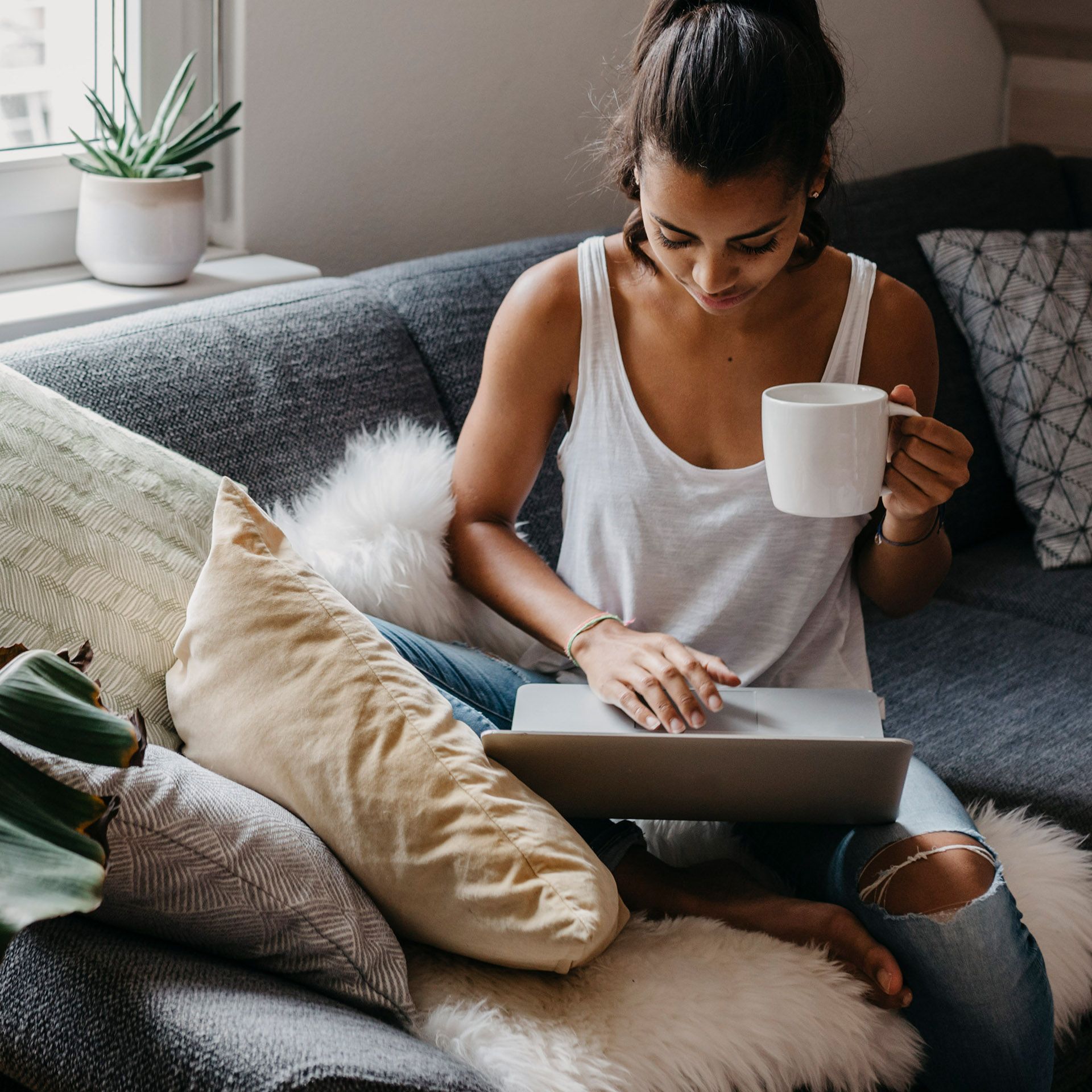 Frau mit Tasse in der Hand am Laptop
