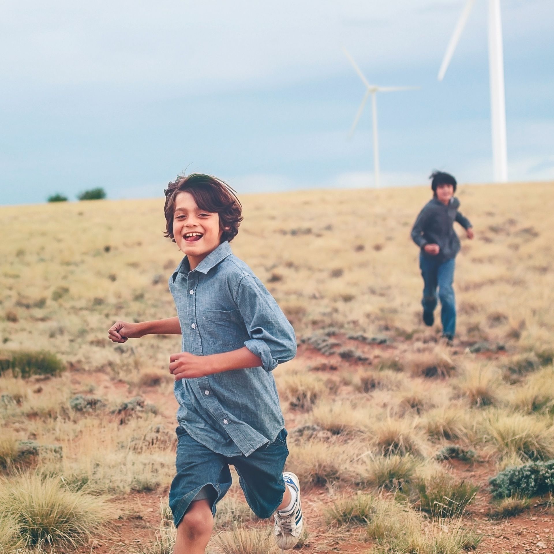 Jungen auf Feld mit Windrädern