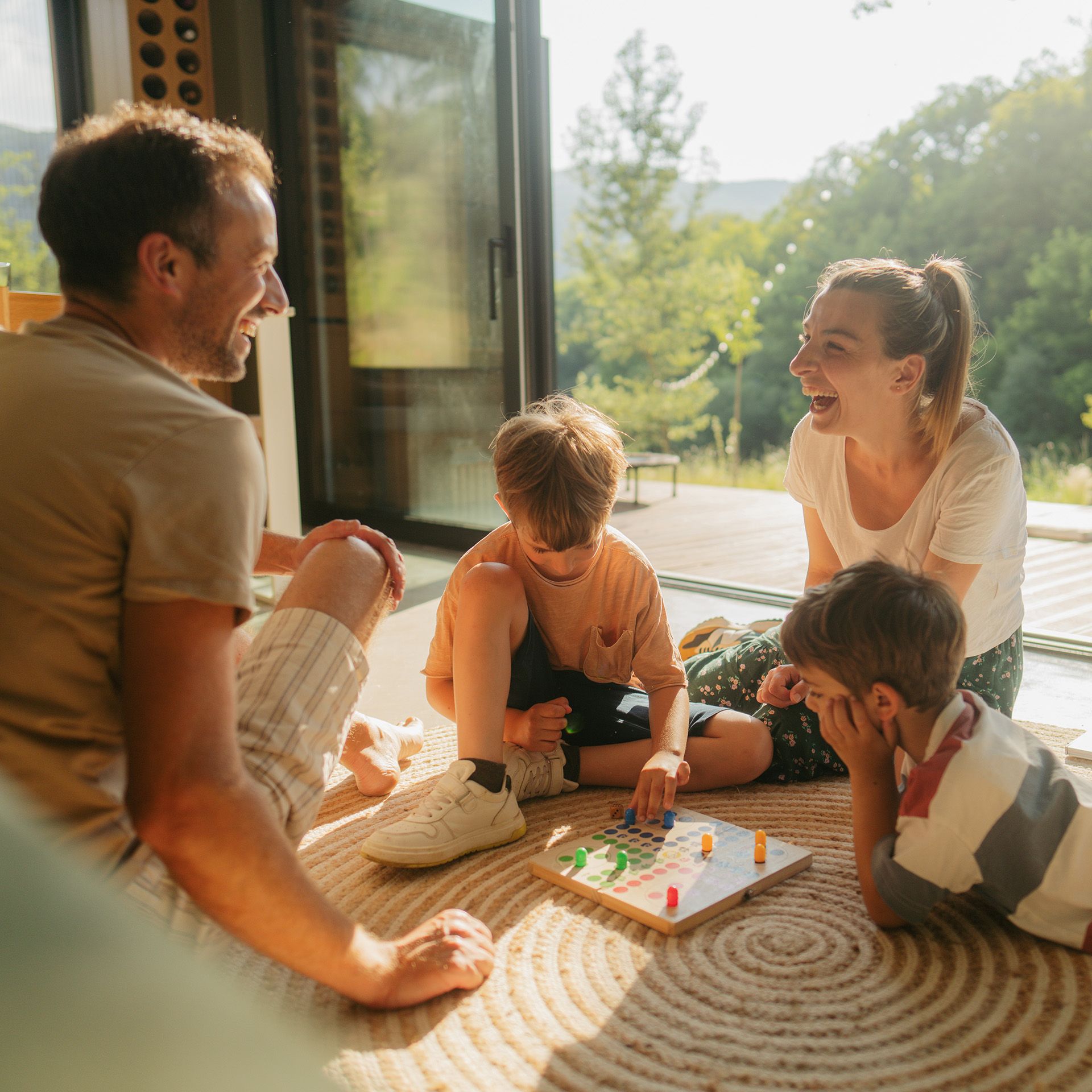 Familie sitzt auf dem Boden und spielt ein Brettspiel