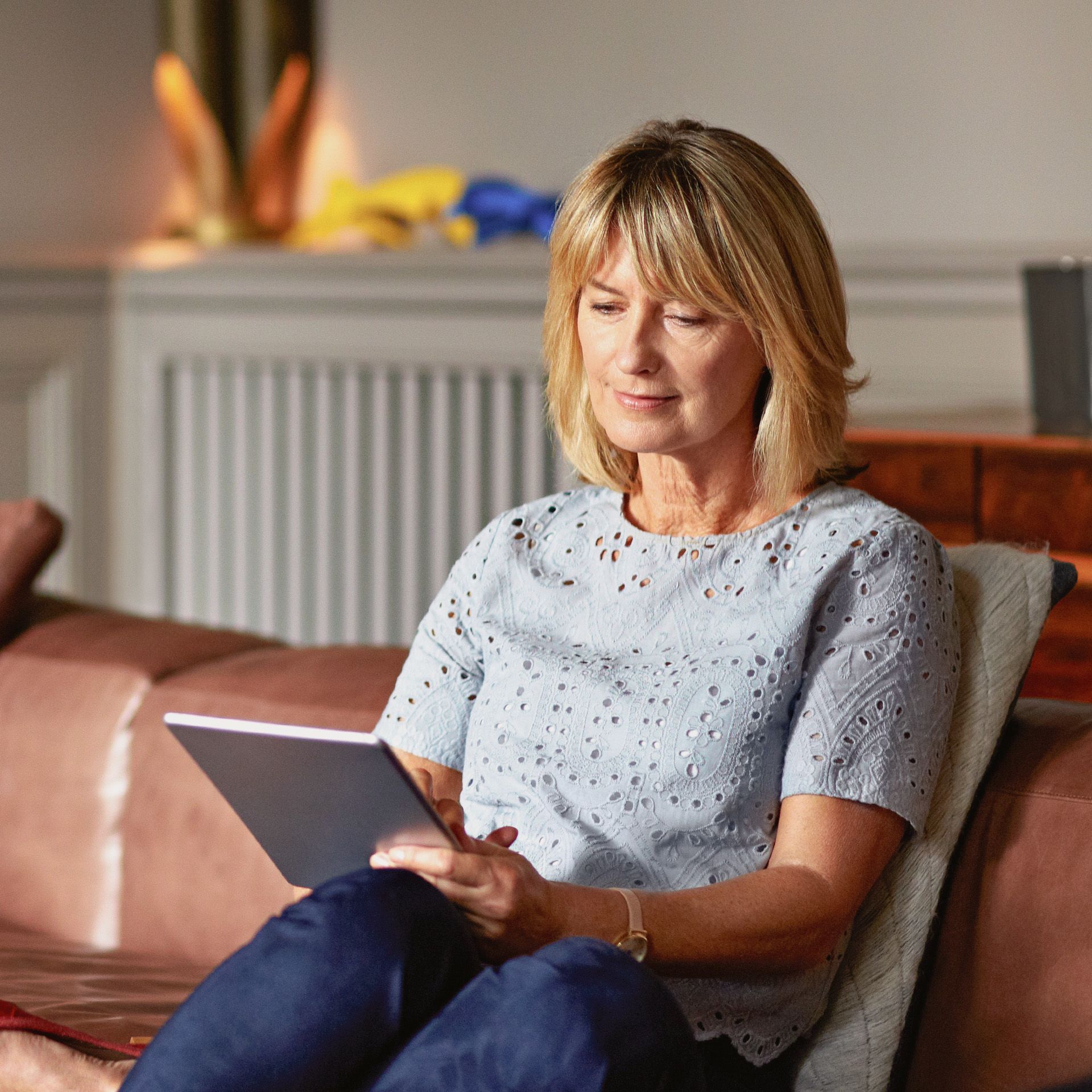 Frau auf Sofa tippt auf Tablet