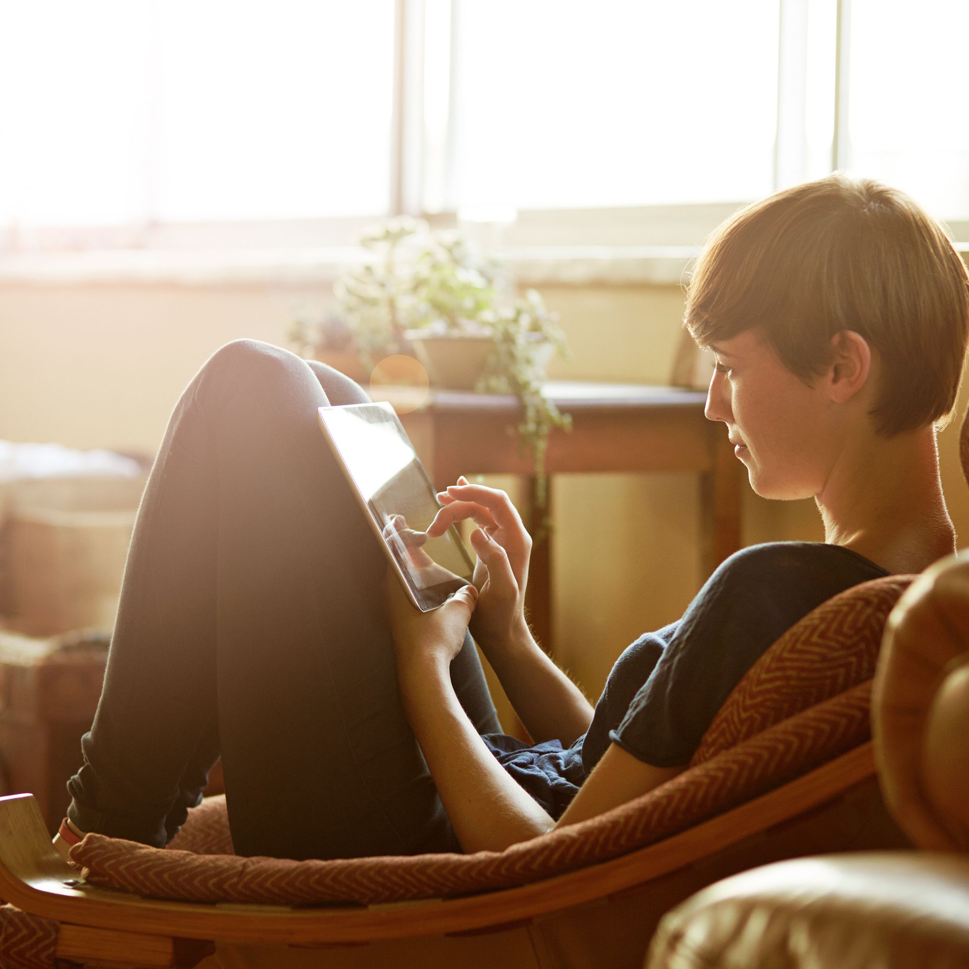 Frau sitzt im Sessel am Tablet