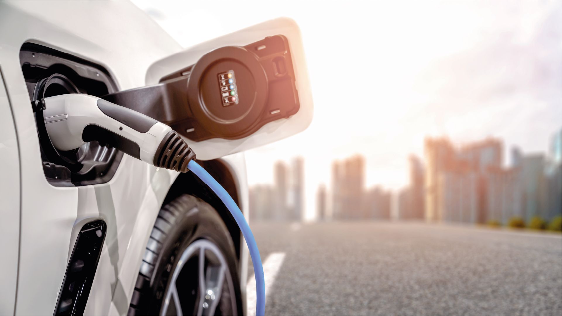 E-Auto lädt vor einer Stadt Skyline