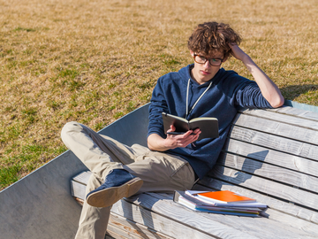 Junge liest ein Buch auf einer Bank