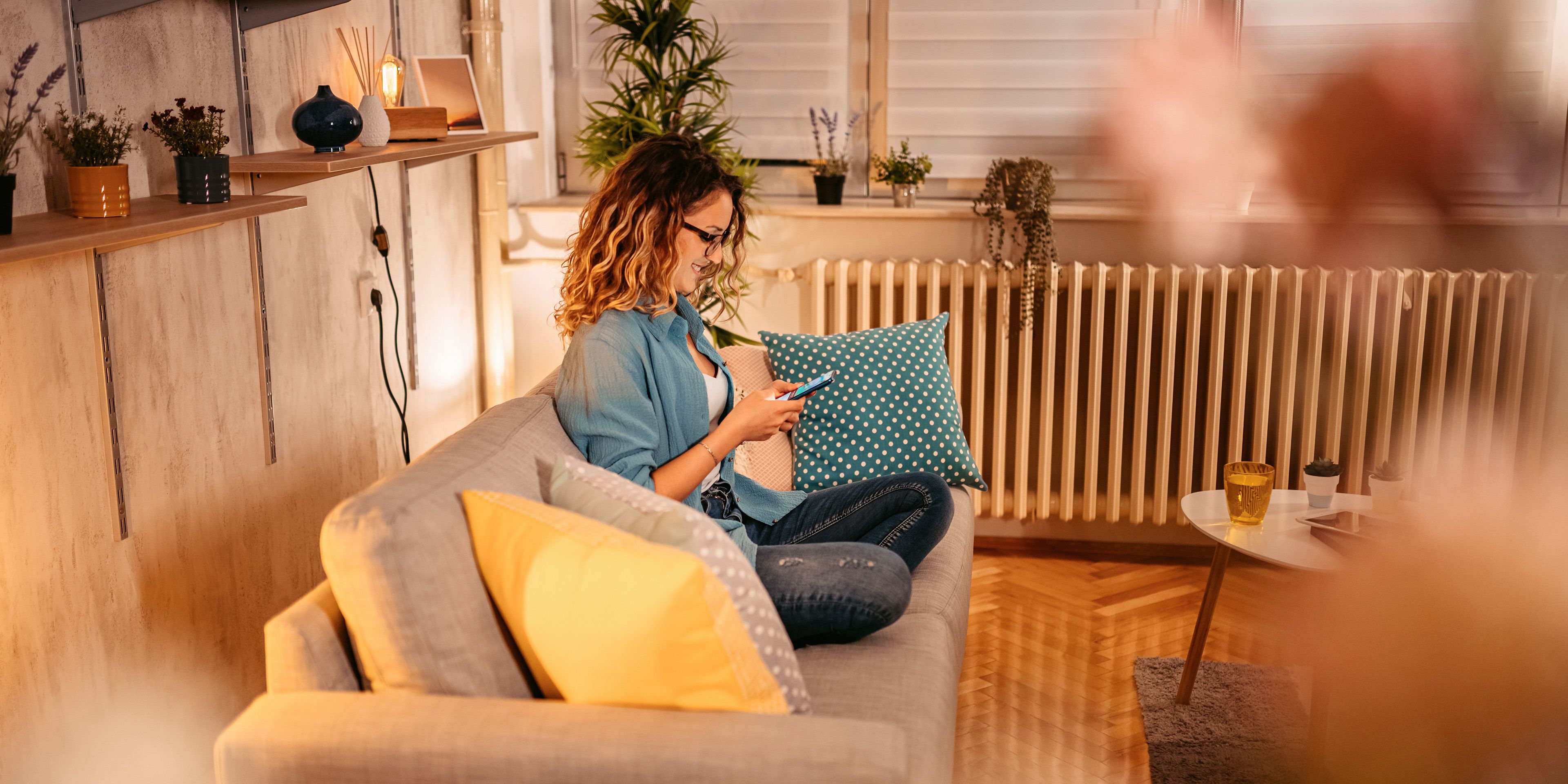 Frau sitzt am Handy auf dem Sofa