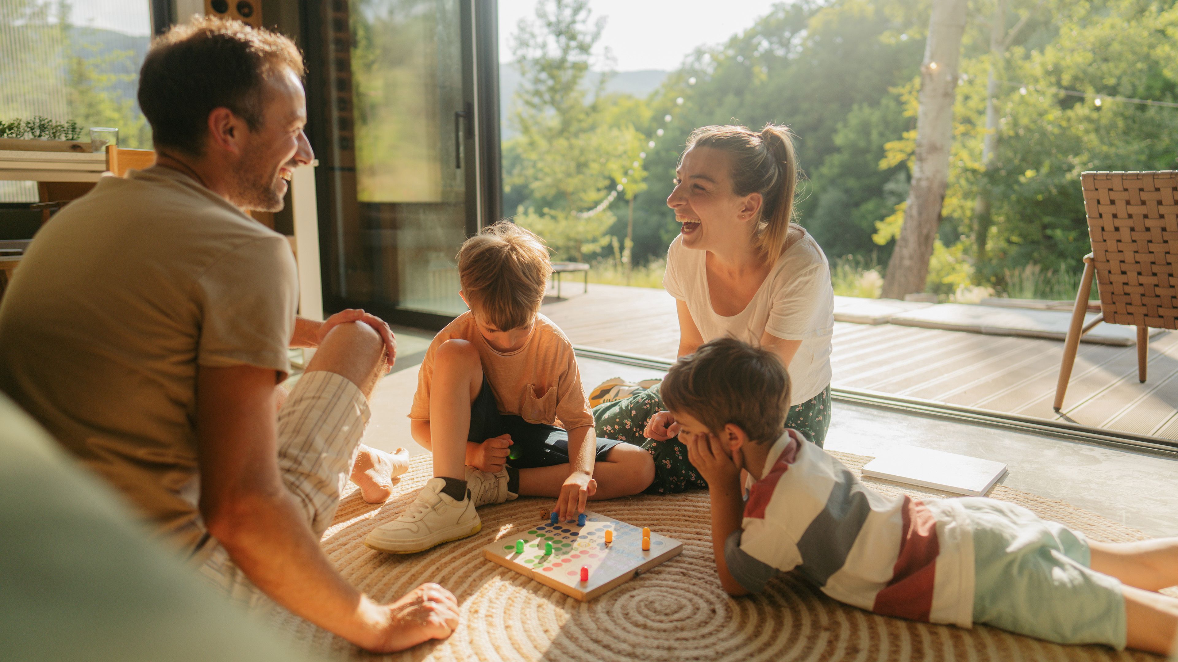 Familie sitzt auf dem Boden und spielt Brettspiel