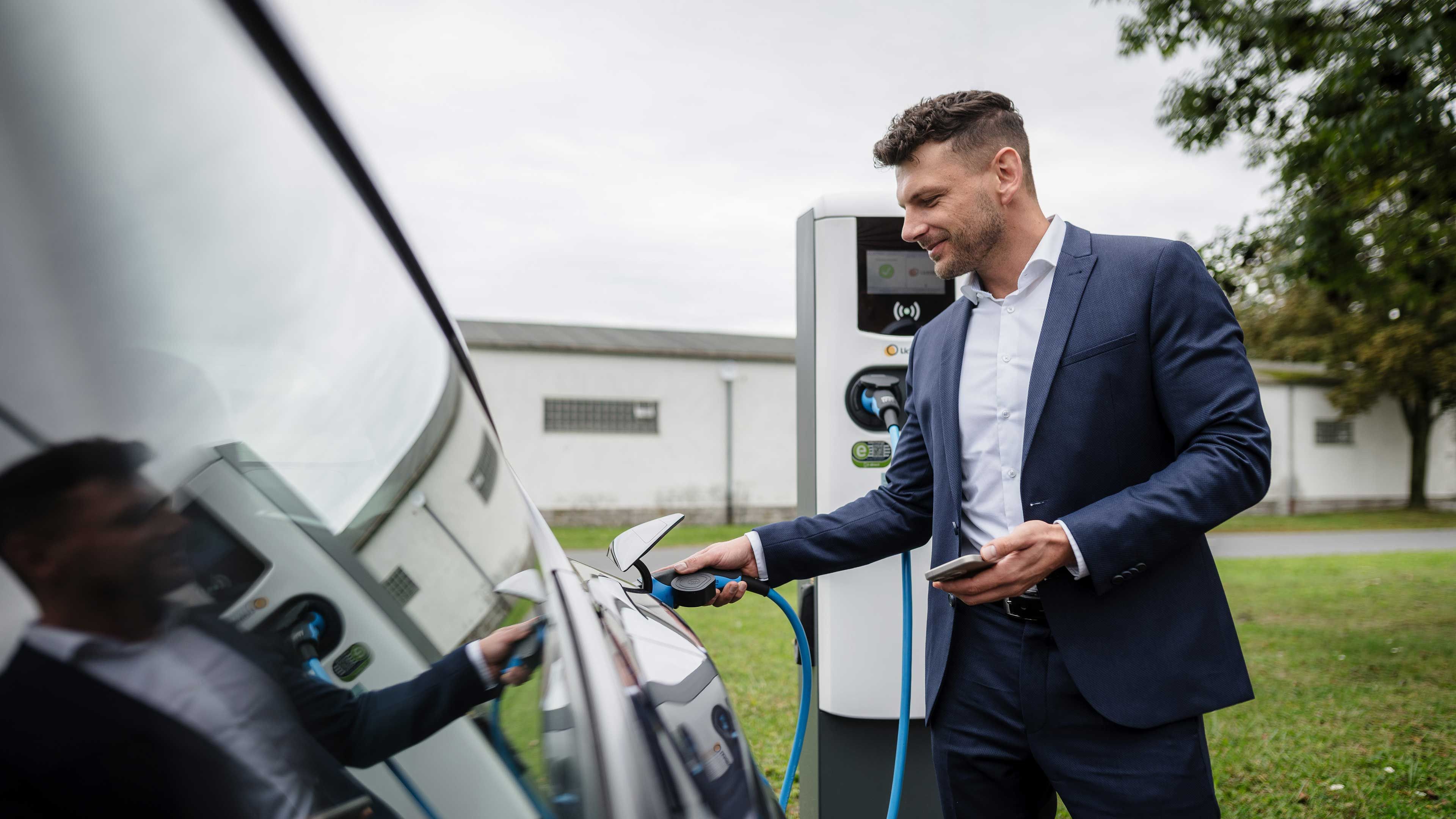 Mann laedt E-Auto an einer Ladestation von LichtBlick