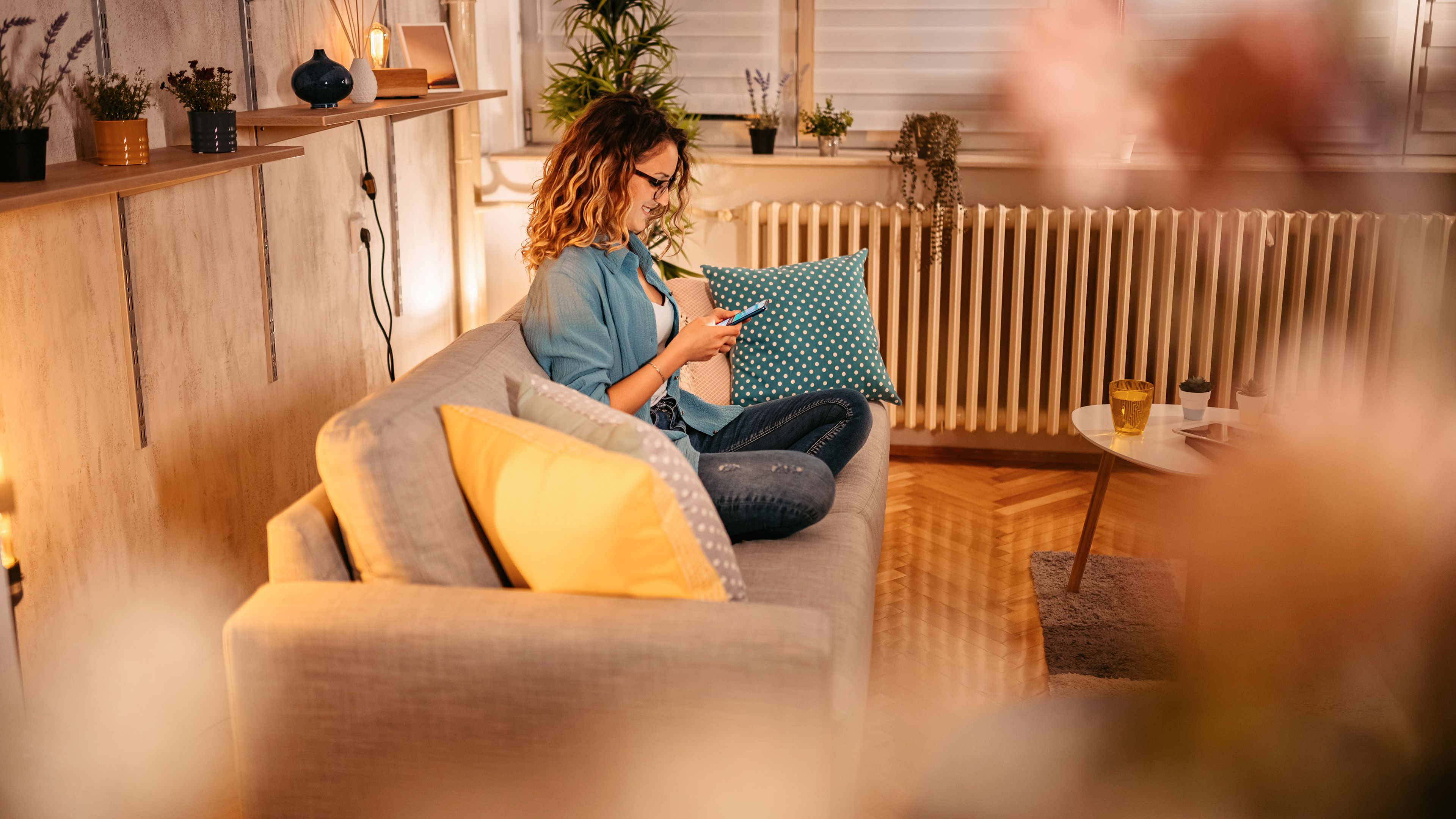 Frau sitzt am Handy auf dem Sofa