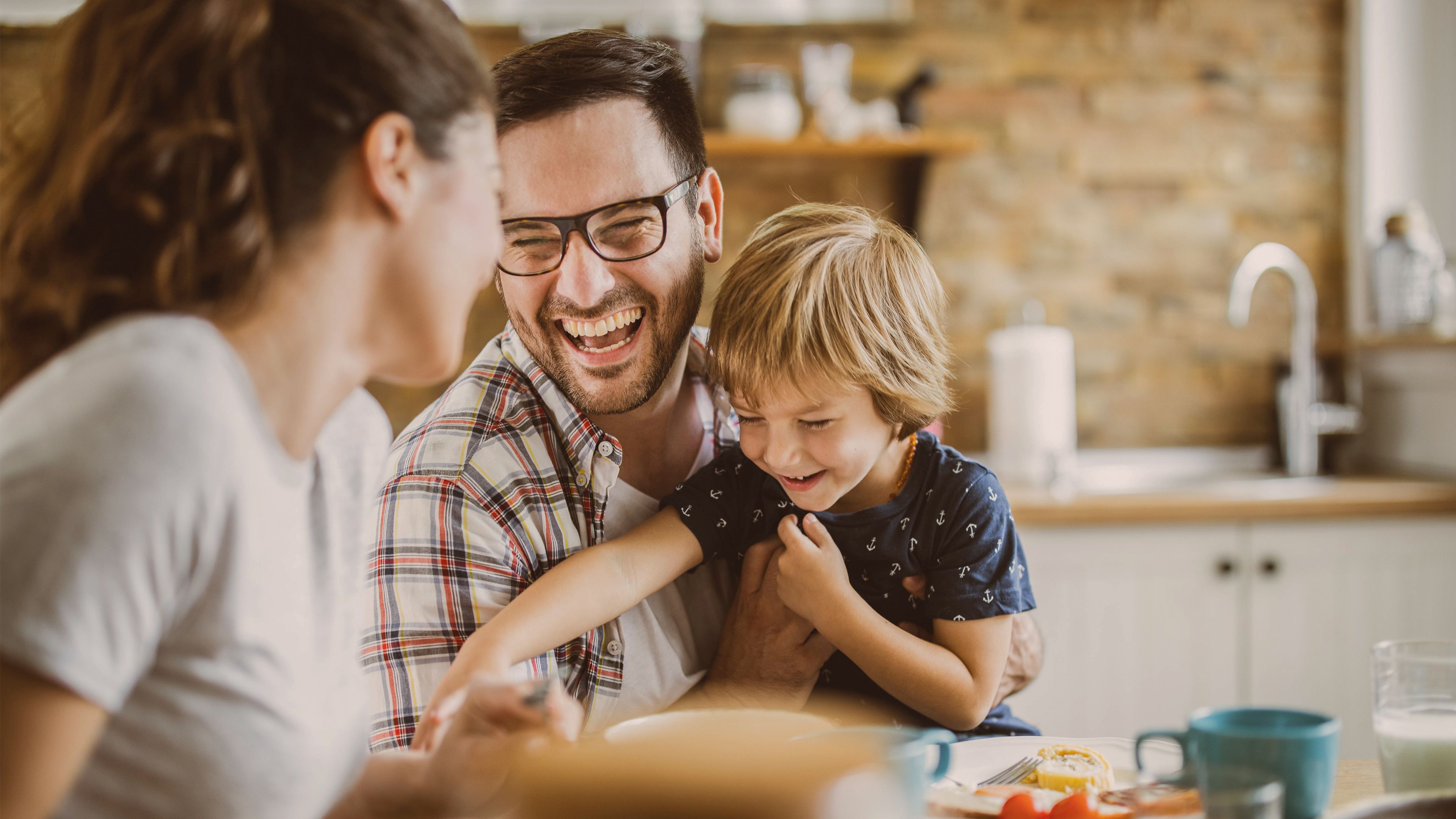 Familie sitzt lachend am Esstisch